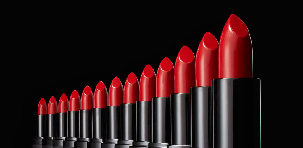 row of red lipsticks on a dark grey background
